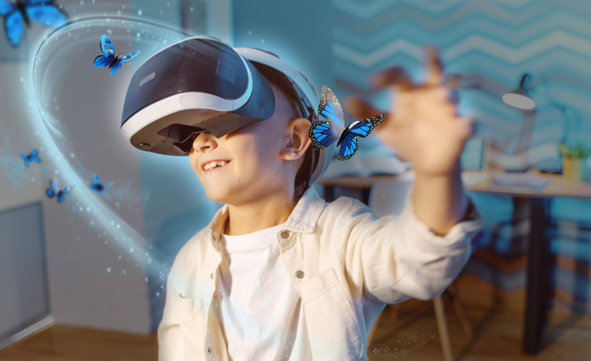 A smiling child wearing a virtual reality headset reaches out toward blue butterflies, blending real and virtual elements in a brightly lit innovation lab.
