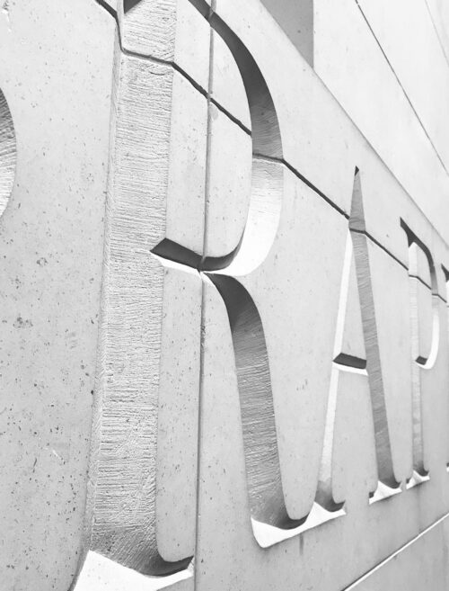 Close-up of large, deeply engraved letters on a textured concrete wall. The photo is in black and white, highlighting the shadows and depth—perfect inspiration for a marketing team seeking bold visual statements.