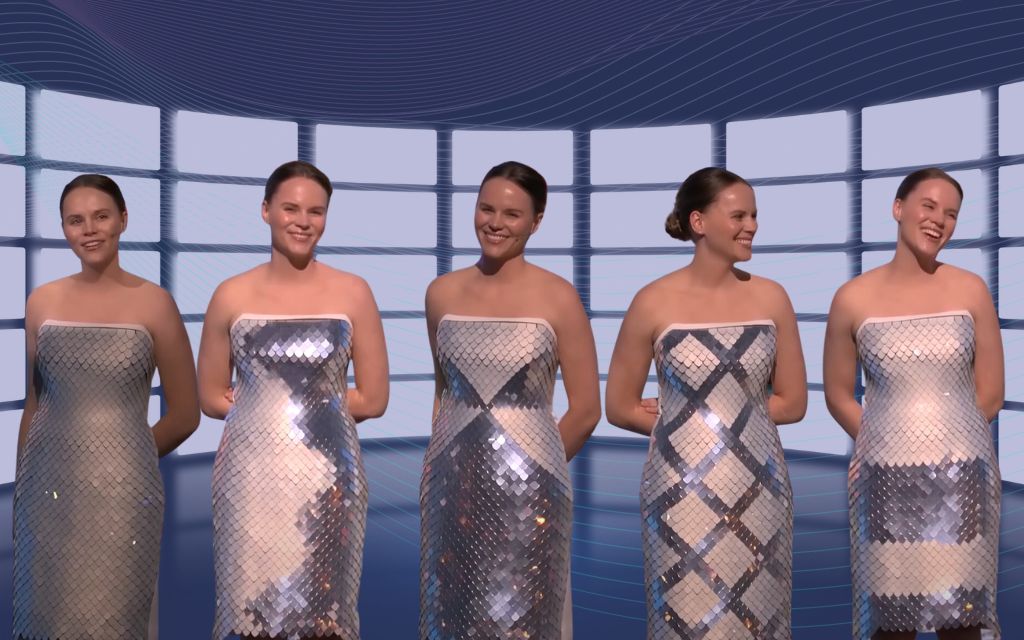 Five women stand side by side, each wearing a strapless, shiny silver or metallic-patterned dress, in front of a backdrop with a curved grid and blue wave design. All are smiling or showing pleasant expressions.