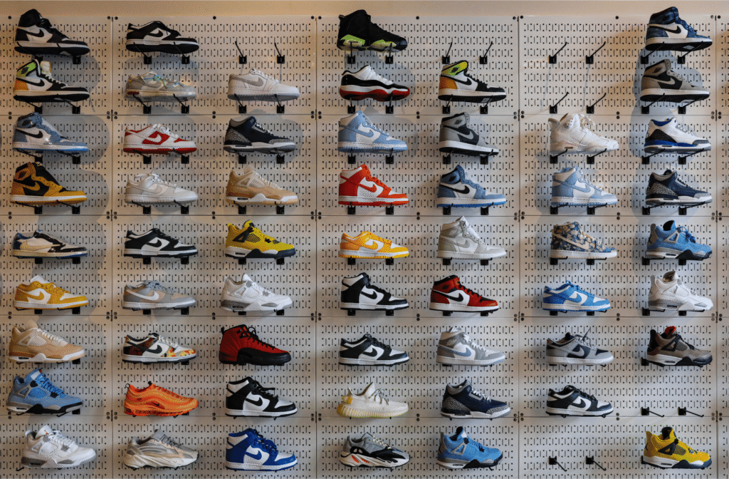 A wall display in a shoe store features dozens of colorful sneakers neatly arranged in rows on white racks, showcasing a variety of styles and colors against a perforated background.